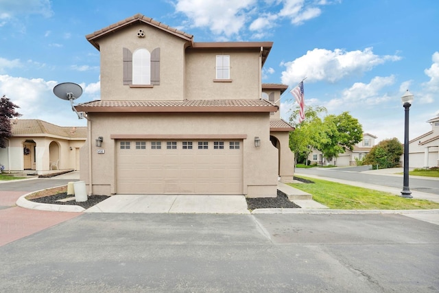mediterranean / spanish-style house with a garage, concrete driveway, stucco siding, and a tiled roof
