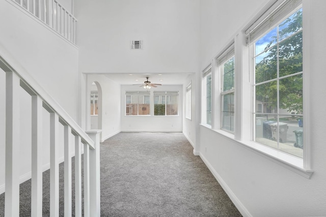 unfurnished sunroom with a towering ceiling, visible vents, baseboards, and carpet floors