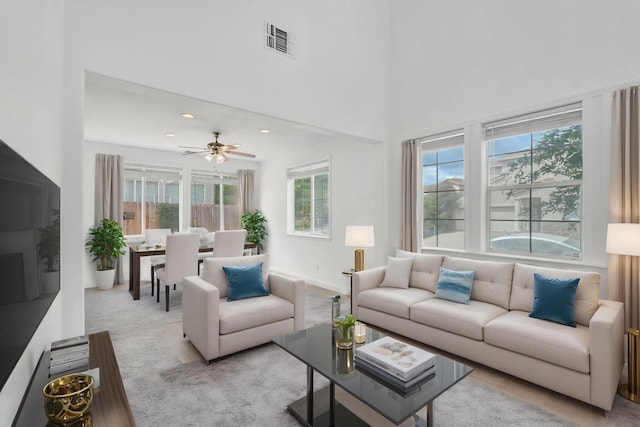 living area featuring visible vents, ceiling fan, light colored carpet, and baseboards