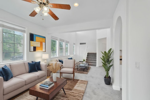 living area with stairs, ceiling fan, carpet, and a healthy amount of sunlight