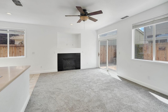 unfurnished living room with visible vents, a tiled fireplace, and light carpet
