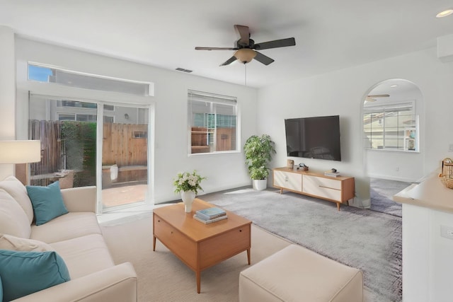 living room featuring a healthy amount of sunlight, visible vents, a ceiling fan, and carpet flooring
