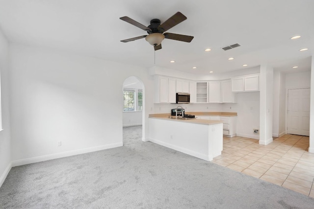kitchen with stainless steel microwave, ceiling fan, visible vents, arched walkways, and stove