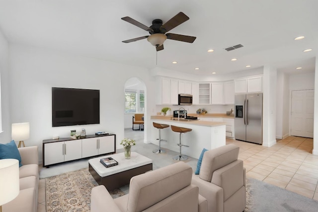 living room featuring light tile patterned floors, visible vents, arched walkways, recessed lighting, and a ceiling fan