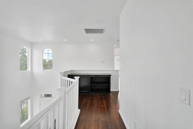 hall with an upstairs landing, visible vents, hardwood / wood-style floors, and baseboards