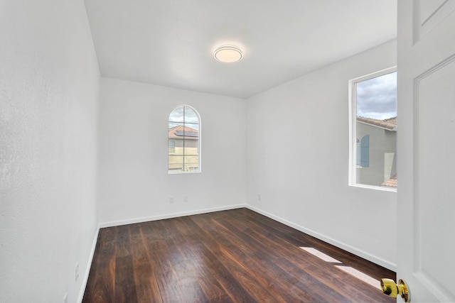 empty room with dark wood-type flooring and baseboards