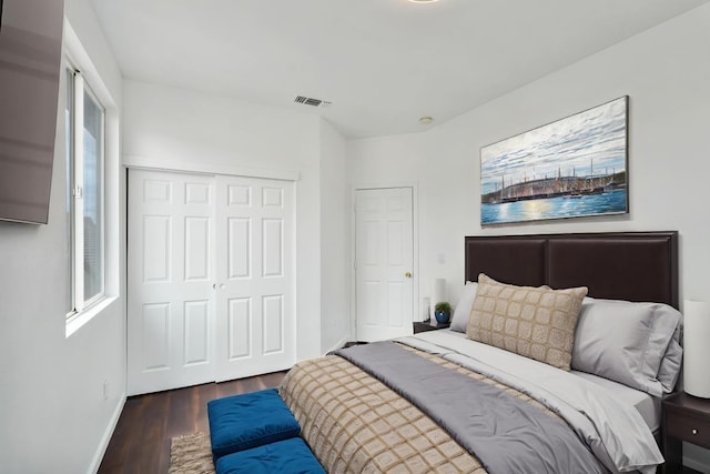 bedroom with dark wood finished floors, visible vents, a closet, and baseboards