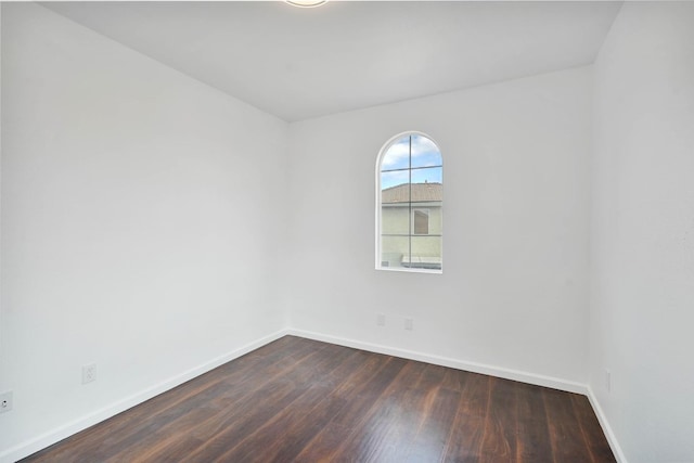 unfurnished room featuring baseboards and dark wood finished floors