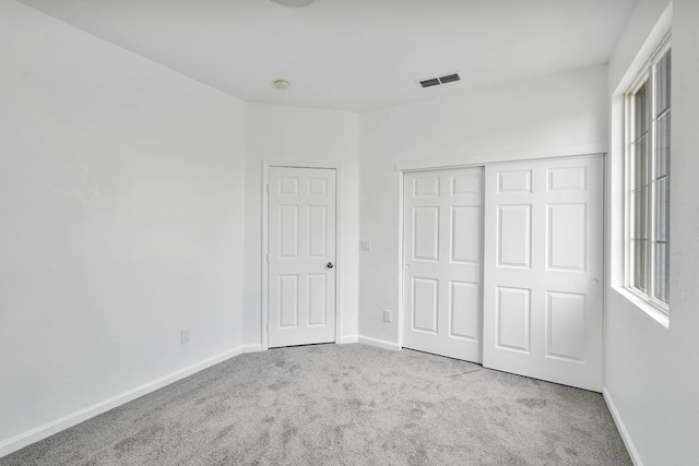 unfurnished bedroom featuring baseboards, visible vents, carpet floors, and a closet