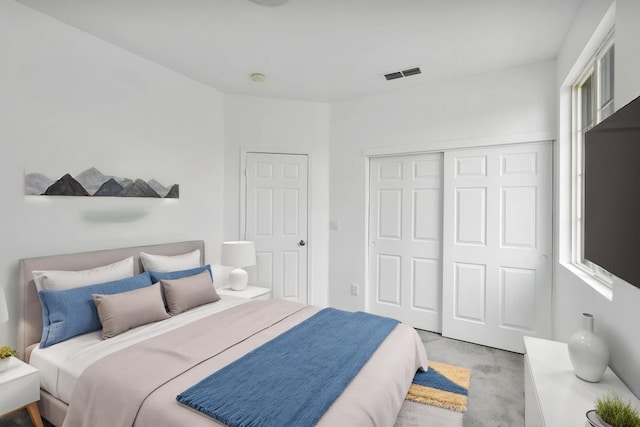 carpeted bedroom with visible vents and a closet