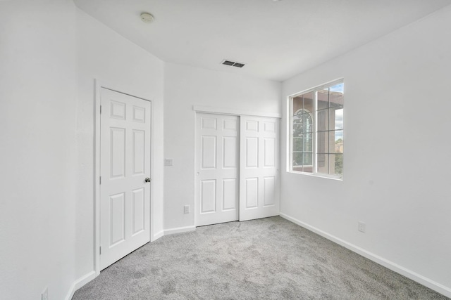 unfurnished bedroom featuring baseboards, visible vents, carpet floors, and a closet