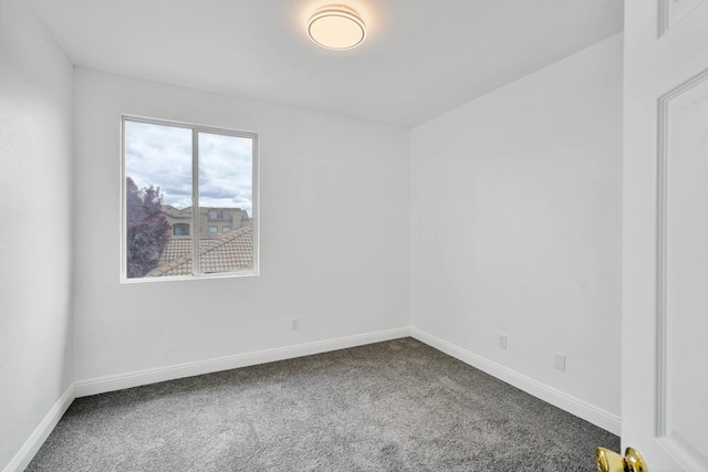 spare room featuring dark colored carpet and baseboards