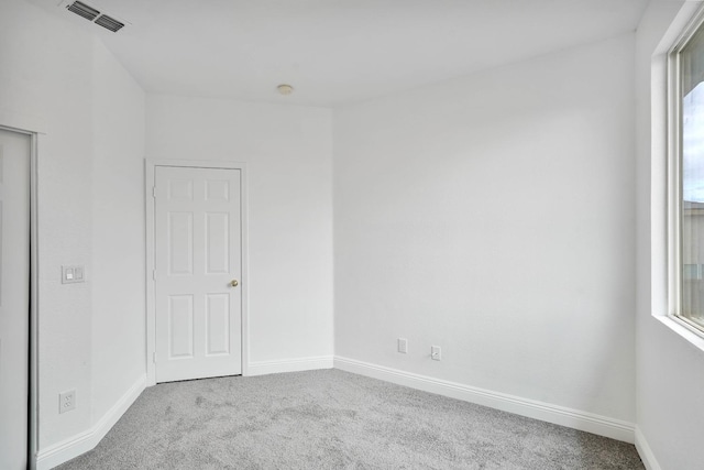 carpeted spare room with visible vents and baseboards