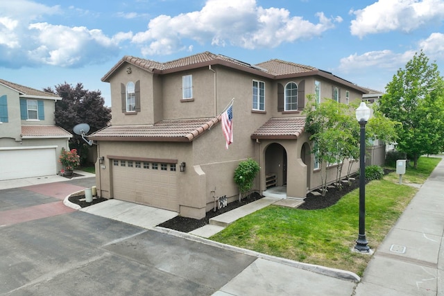 mediterranean / spanish-style home with a tile roof, a front yard, a garage, concrete driveway, and stucco siding