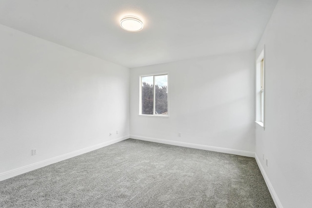 carpeted spare room featuring baseboards