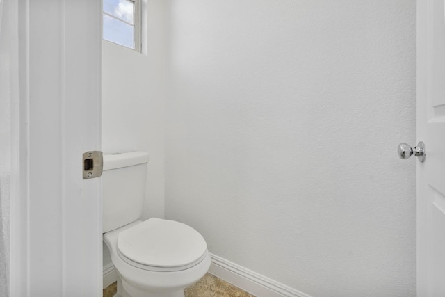 bathroom featuring toilet and baseboards