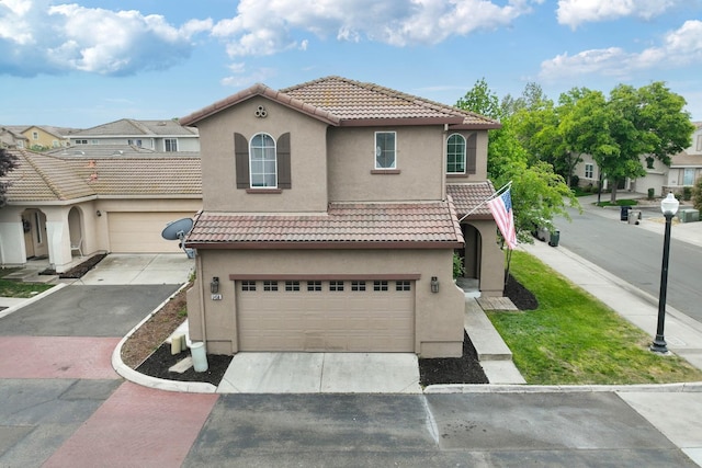 mediterranean / spanish-style house featuring stucco siding, a tile roof, driveway, and an attached garage