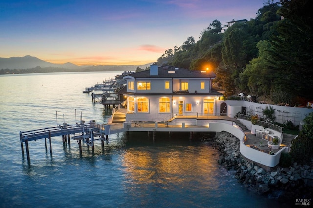 rear view of house with a chimney, stairs, boat lift, and a water and mountain view