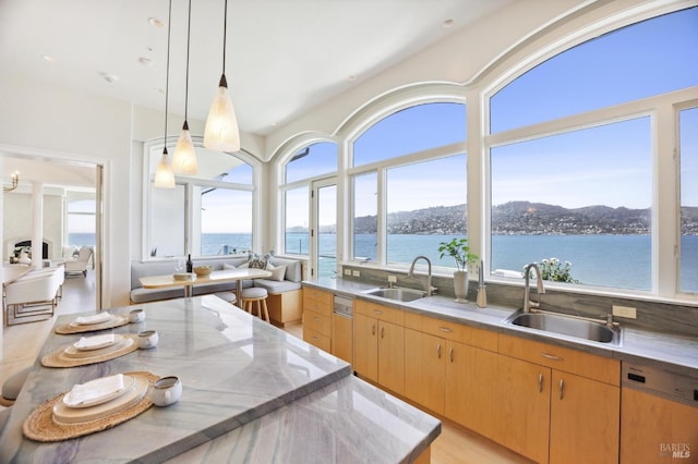 kitchen with paneled dishwasher, pendant lighting, a sink, and a water view