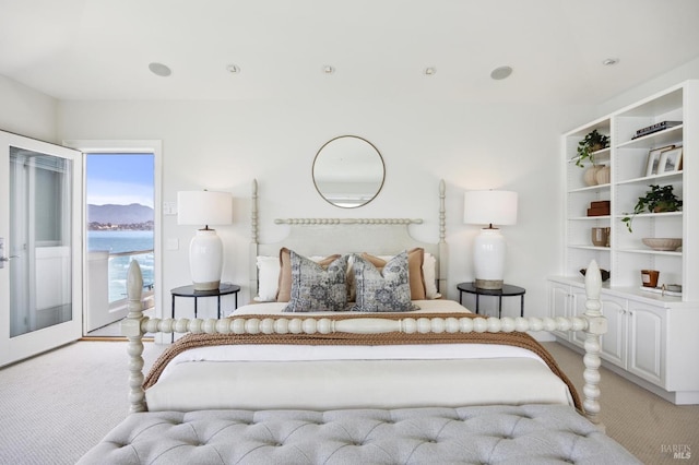 bedroom featuring light carpet, access to exterior, and a water view