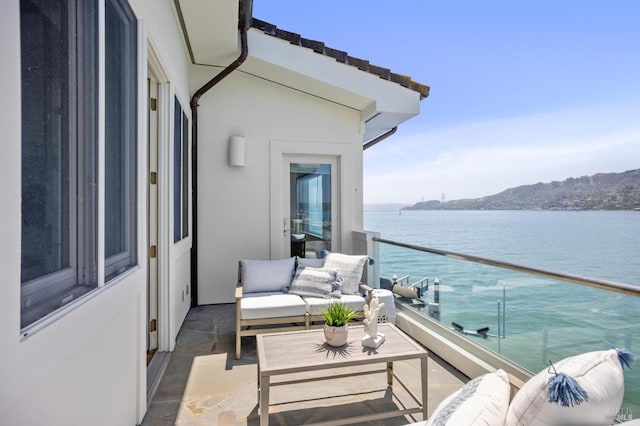 balcony featuring an outdoor living space and a water view