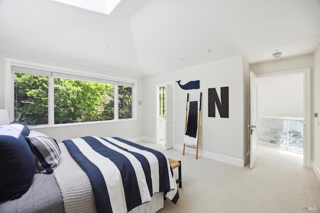 bedroom with vaulted ceiling with skylight, baseboards, multiple windows, and light colored carpet