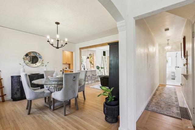 17 Hanns Ave, Vallejo, CA 94590 - dining space with a chandelier, light wood-style flooring, arched walkways, and a wealth of natural light