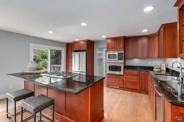 kitchen featuring appliances with stainless steel finishes, a sink, light wood finished floors, and recessed lighting