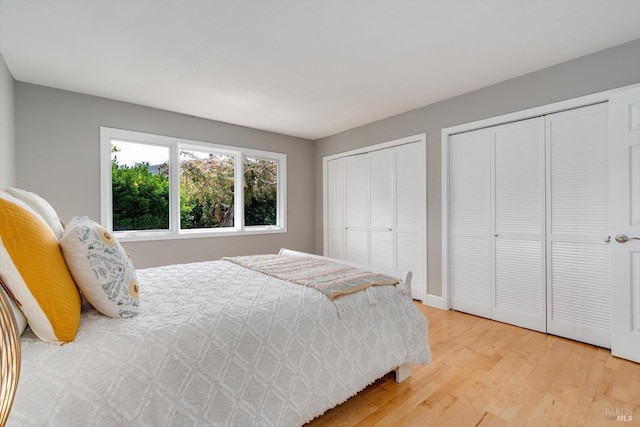 bedroom featuring light wood-style flooring and multiple closets