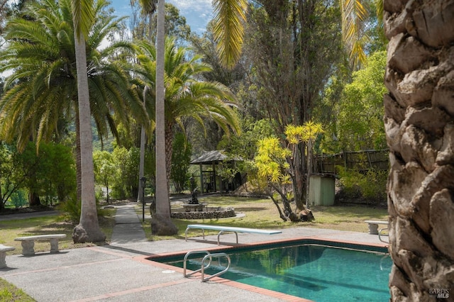 outdoor pool featuring fence and a diving board
