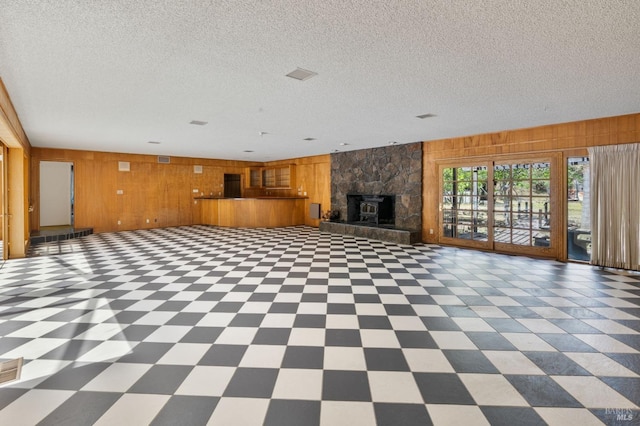 unfurnished living room with wood walls, tile patterned floors, a textured ceiling, and a fireplace