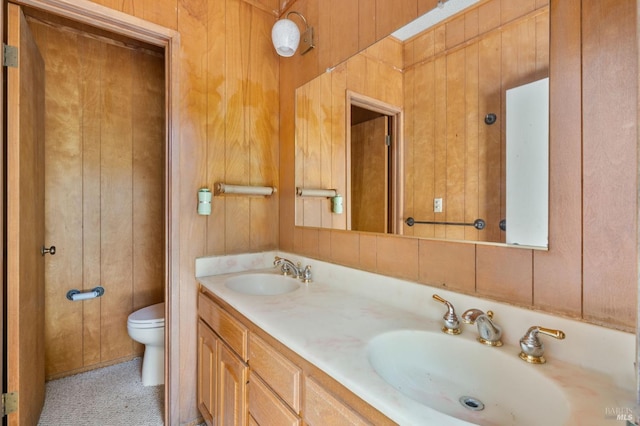 full bath featuring toilet, wood walls, and a sink