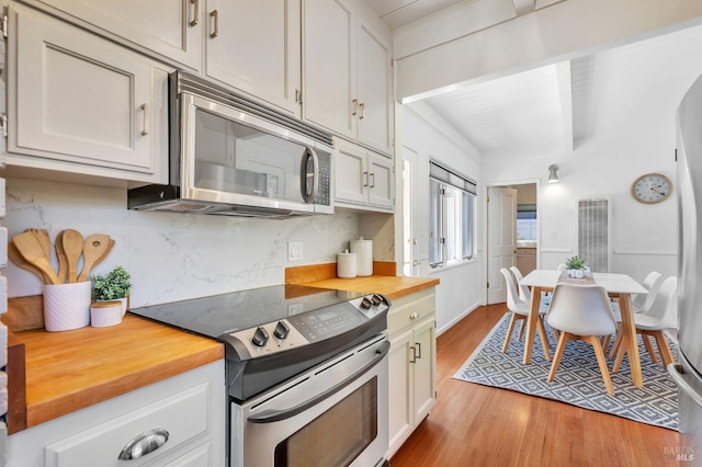kitchen featuring wood counters, backsplash, appliances with stainless steel finishes, and light wood-style flooring