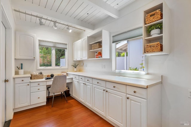 kitchen featuring white cabinets, open shelves, light wood finished floors, and built in desk