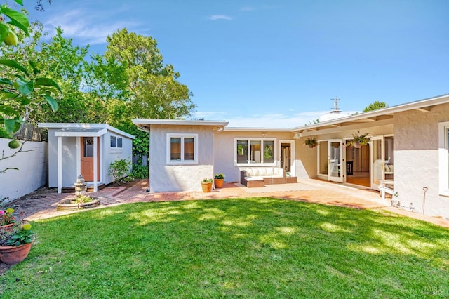 back of house with an outbuilding, a patio area, a yard, a shed, and stucco siding