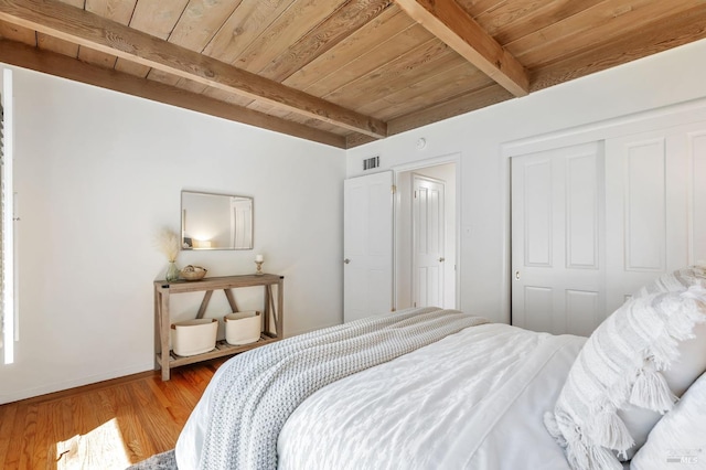 bedroom with wooden ceiling, baseboards, beamed ceiling, and a closet