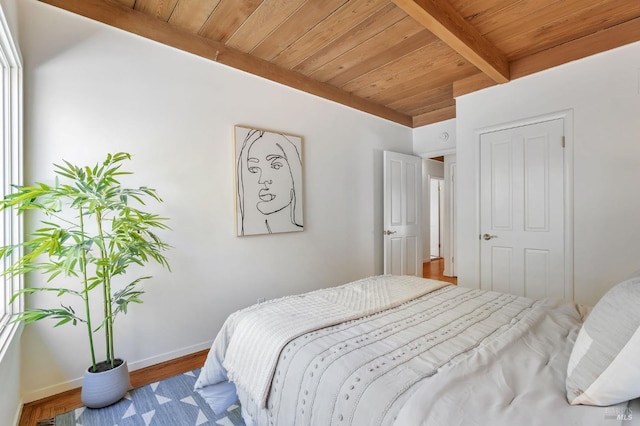 bedroom featuring wood ceiling, wood finished floors, baseboards, and beam ceiling