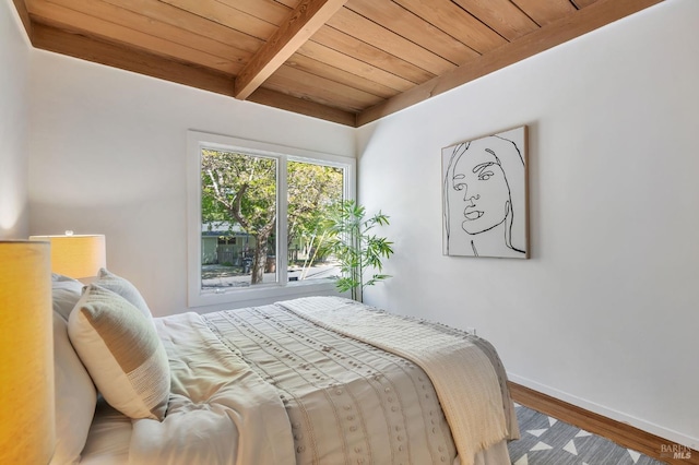bedroom with wood ceiling, baseboards, wood finished floors, and beamed ceiling