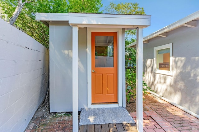 entrance to property featuring fence and stucco siding