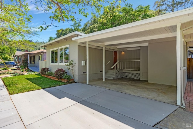 view of front facade featuring a front lawn, an attached carport, and concrete driveway