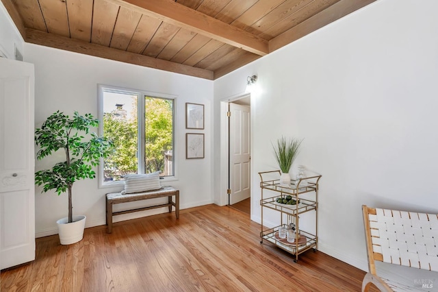 interior space featuring beamed ceiling, light wood-type flooring, baseboards, and wooden ceiling