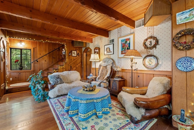 sitting room with wallpapered walls, wood walls, beamed ceiling, hardwood / wood-style flooring, and stairs