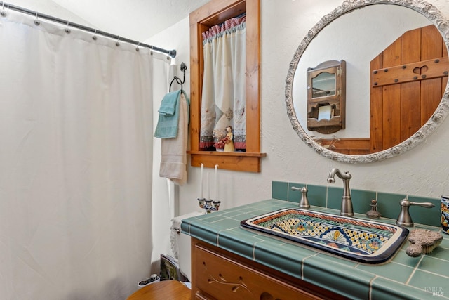 full bathroom featuring a textured wall, vanity, and a shower with shower curtain