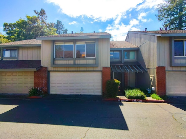 multi unit property with an attached garage, brick siding, and aphalt driveway