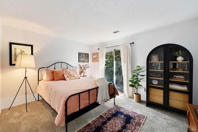 bedroom featuring a textured ceiling, visible vents, light carpet, and access to exterior