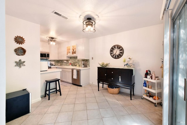kitchen with white cabinets, stainless steel appliances, tasteful backsplash, visible vents, and light countertops