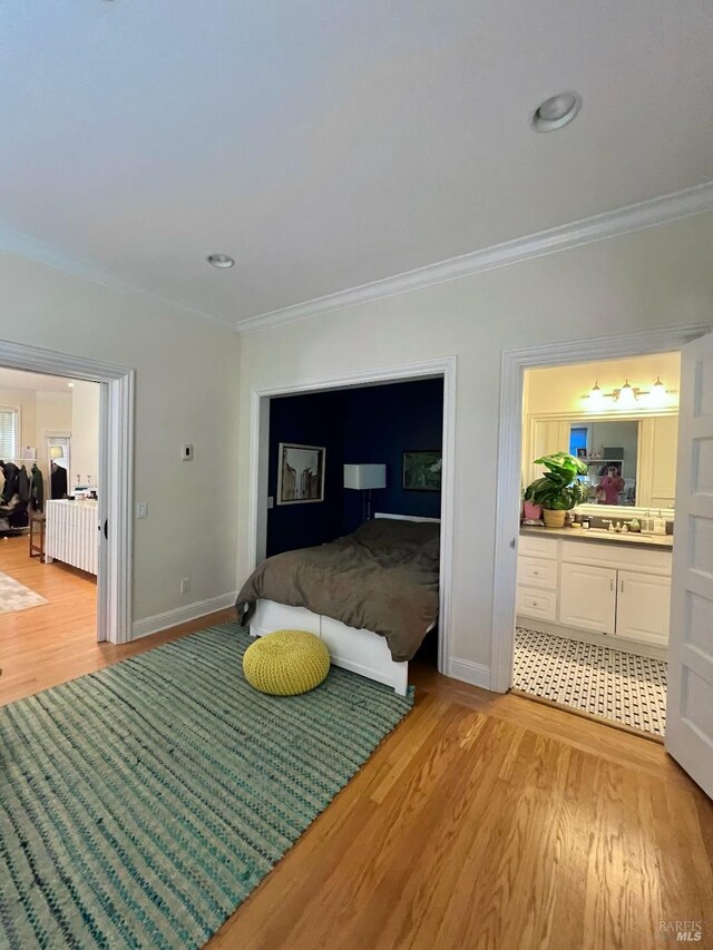 bedroom with baseboards, light wood-style floors, and crown molding