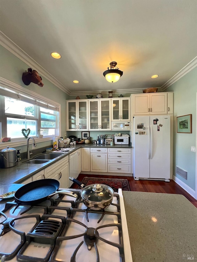 kitchen with glass insert cabinets, white appliances, a sink, and crown molding