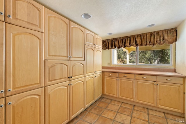 kitchen with recessed lighting, light brown cabinetry, a textured ceiling, and light countertops