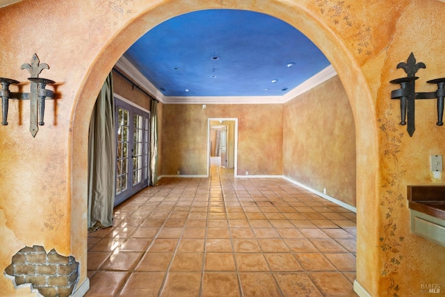 tiled spare room with arched walkways, baseboards, ornamental molding, and french doors